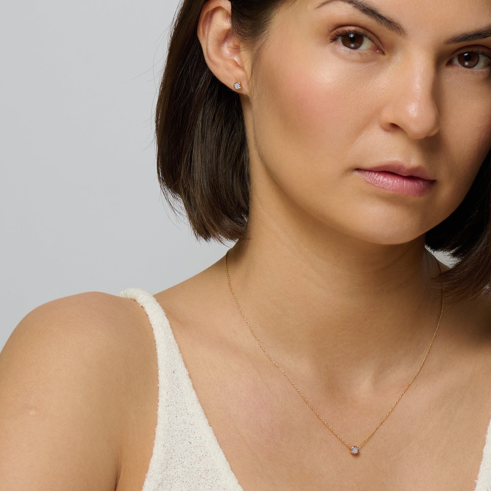 A matching set of gold diamond stud earring and gold diamond pendant chain necklace